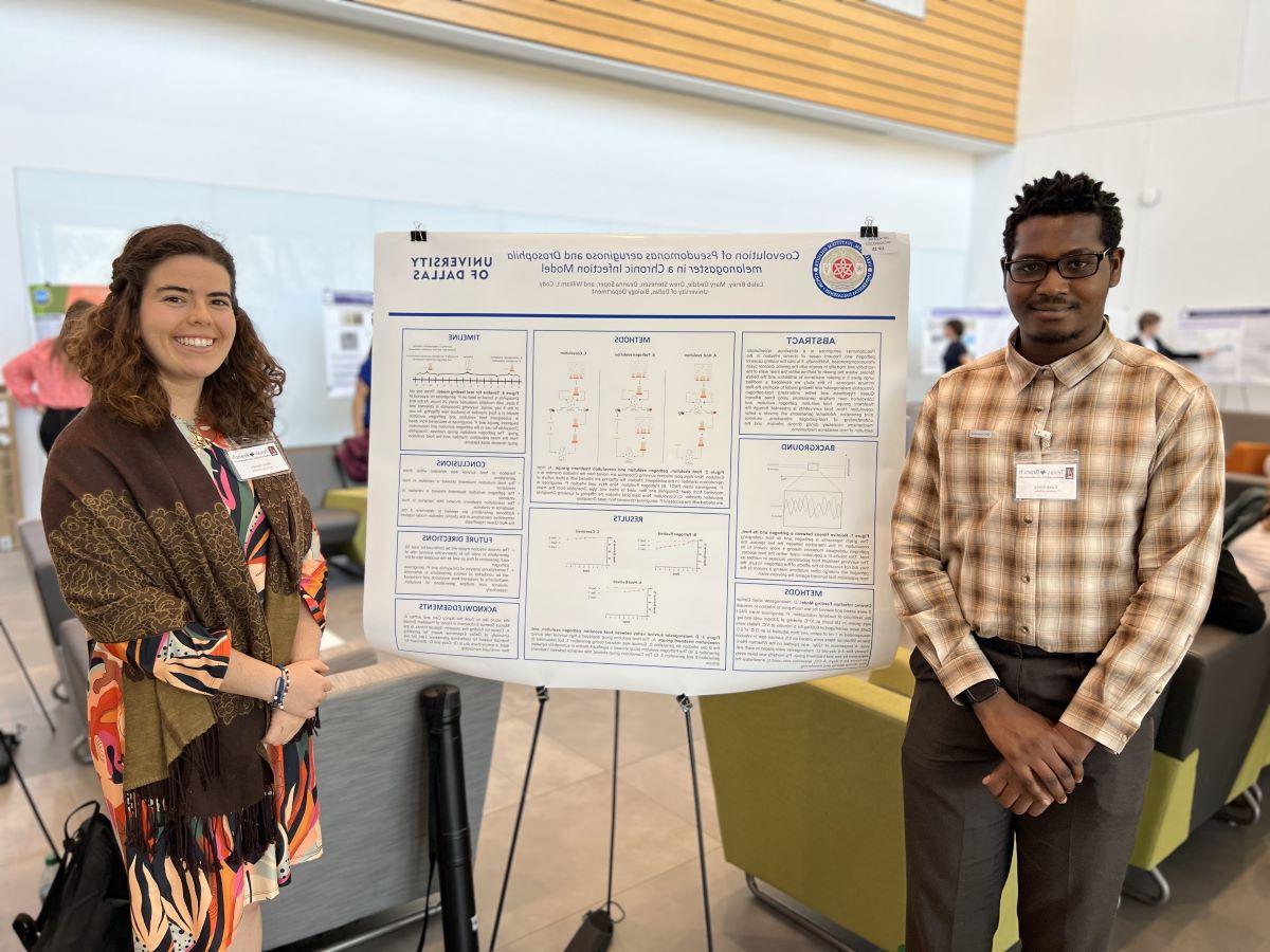 Two undergraduates in front of presentation poster